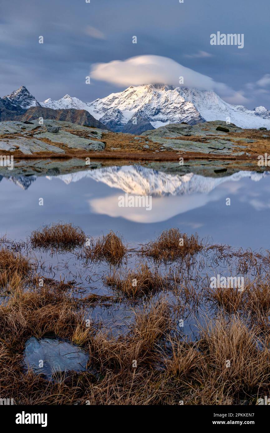 Vette innevate che si riflettono in uno stagno in autunno, Alpe Fora, Valmalenco, Valtellina, provincia di Sondrio, Lombardia, Italia, Europa Foto Stock