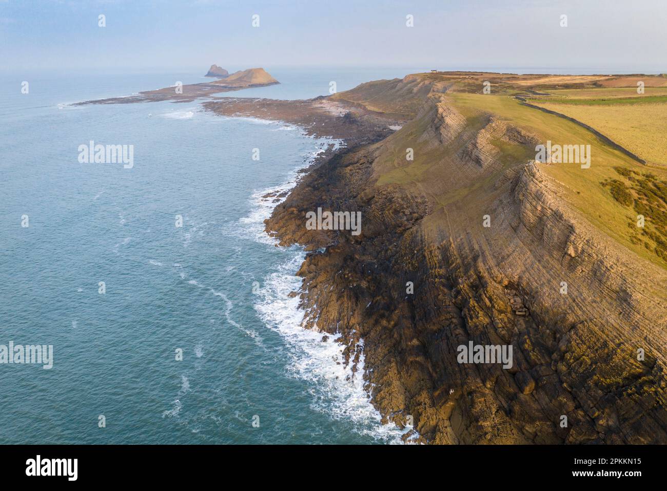 Vista aerea delle spettacolari scogliere calcaree di Gower, guardando verso Worm's Head, Gower Peninsula, Galles del Sud, Regno Unito, Europa Foto Stock
