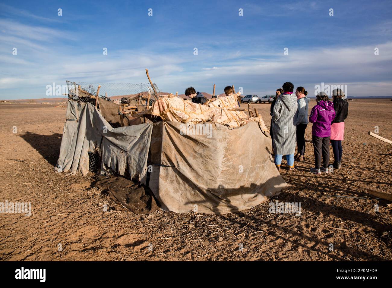 Un gruppo di turisti si radunano fuori tende di fortuna in un campo berbero in Marocco Foto Stock