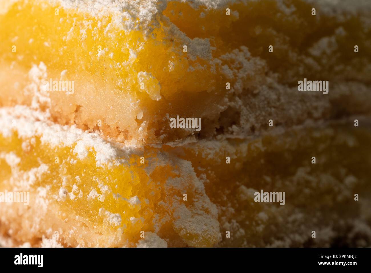 100mm obiettivo Macro close-up Lemon Bar a doppio strato con ripieno giallo dolce e guarnizione dello zucchero a potenza Foto Stock