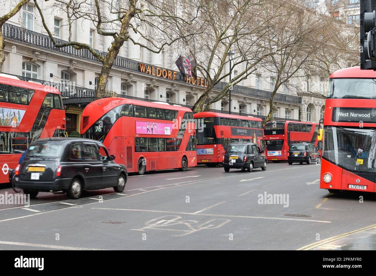 Londra, Regno Unito - 17 marzo 2023; autobus a due piani rossi multipli di Londra di fronte al Waldorf Hotel con taxi con sfocatura movimento Foto Stock