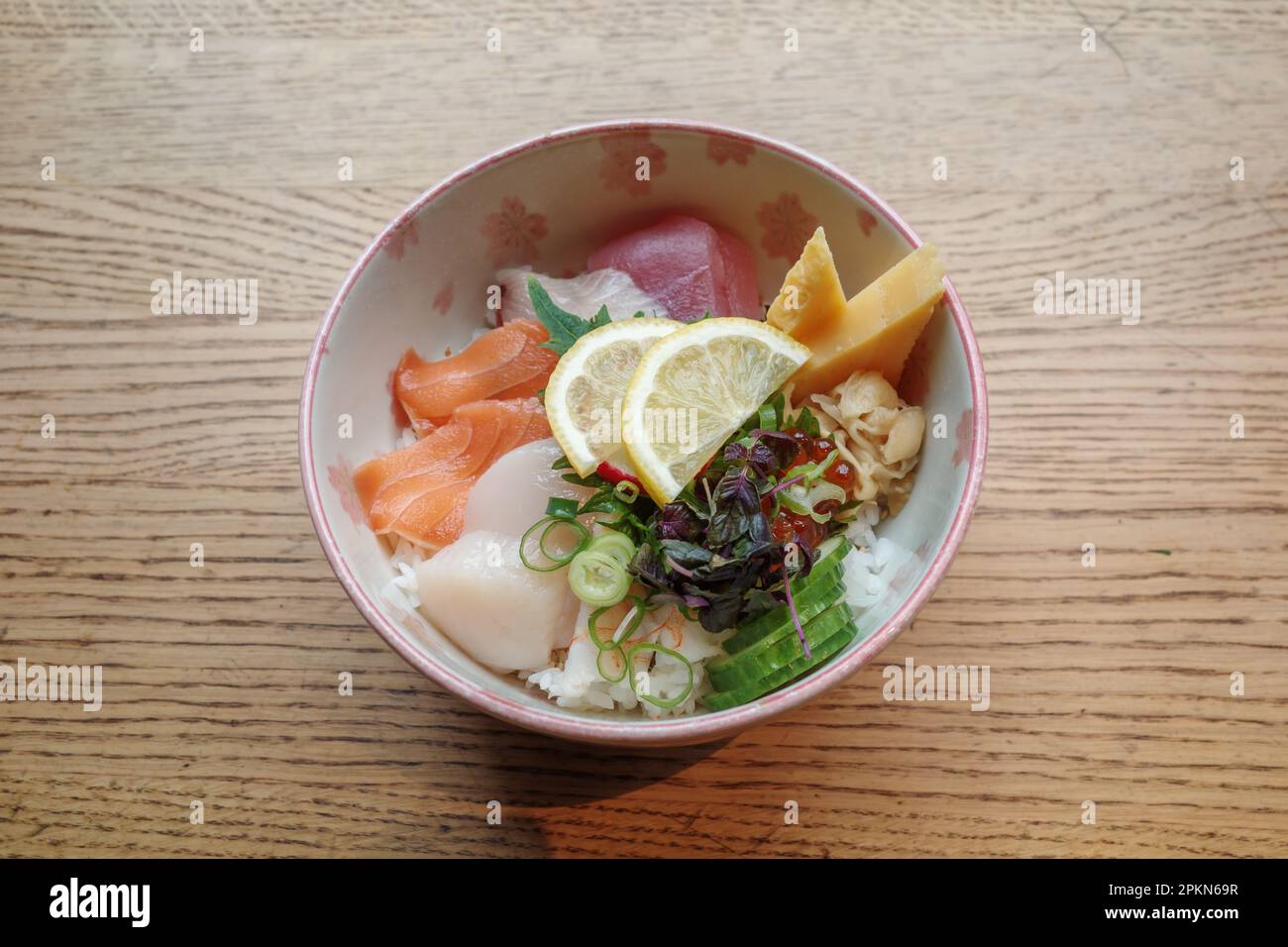 Vista dall'alto di Sashimi Don, Danburi o ciotola di riso giapponese con varie fette fresche di pesce crudo, gamberi, calamari, capesante e uova di tamago, sul legno. Foto Stock