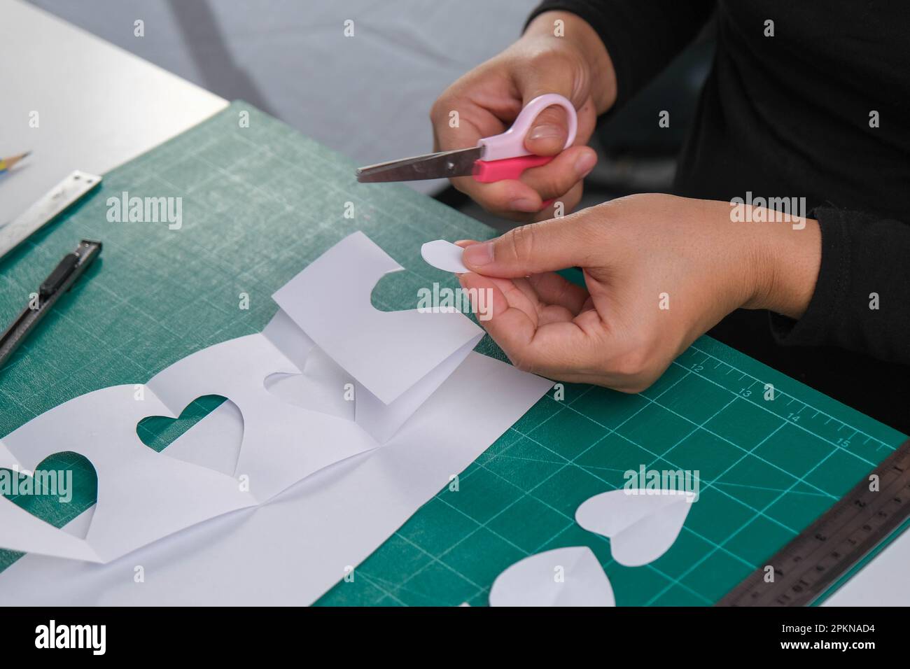 Una donna taglia una carta bianca a forma di cuore con forbici per  decorare. Biglietto di auguri per San Valentino o idea regalo per le feste  Foto stock - Alamy