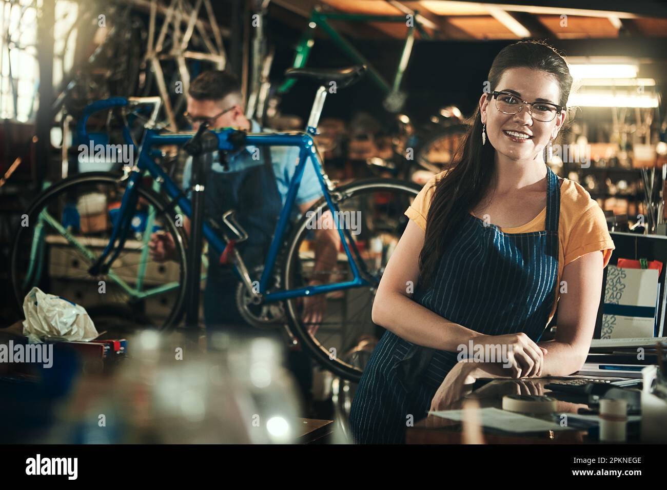 Ti consente di riportare la tua moto alla sua gloria precedente. Ritratto  di una giovane donna che lavora in un negozio di riparazione di biciclette  con la sua collega sullo sfondo Foto