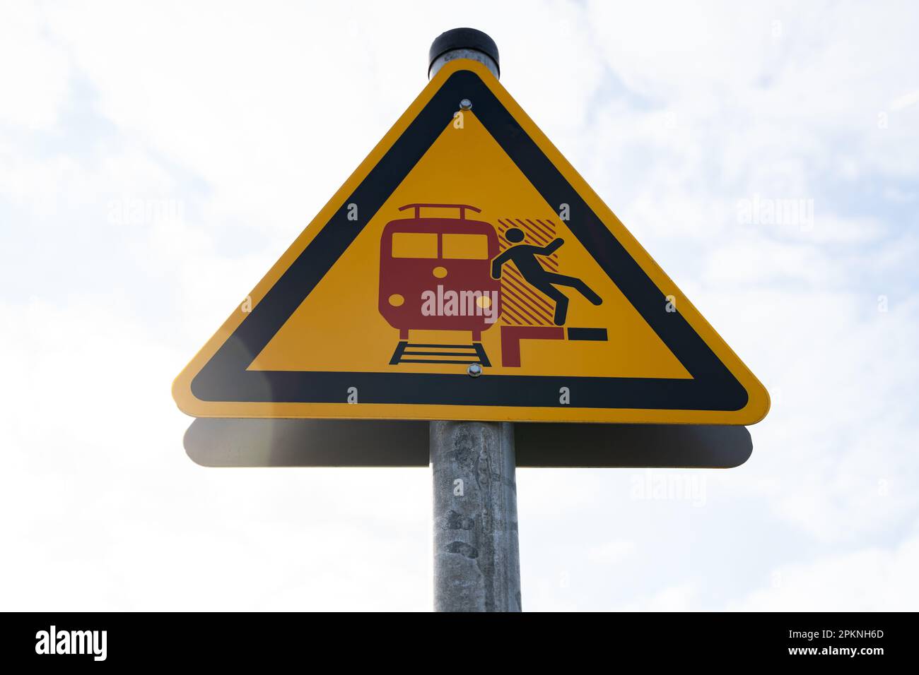 Segnale di avvertimento giallo triangolare sulla piattaforma che indica attenzione ai treni in arrivo e in transito Foto Stock