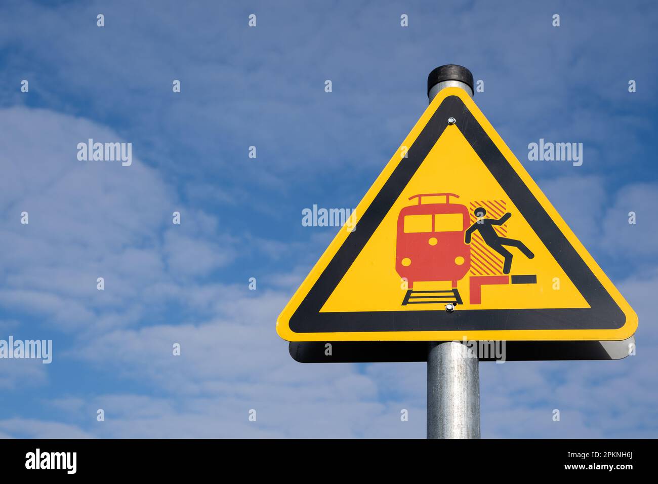 Segnale di avvertimento giallo triangolare per i passeggeri su una piattaforma tedesca che significa attenzione all'arrivo e al transito dei treni Foto Stock