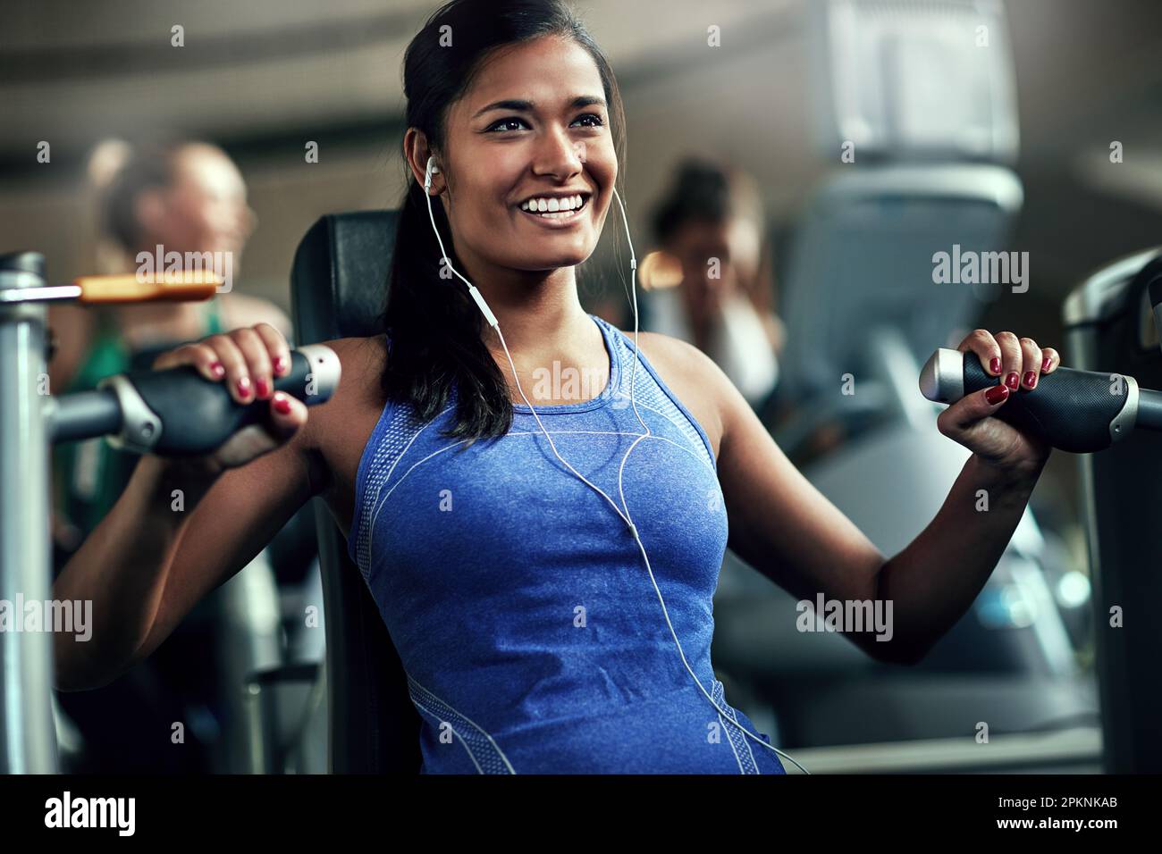 Tutto paga fuori. una giovane donna che si allenava con una pressione toracica in palestra. Foto Stock