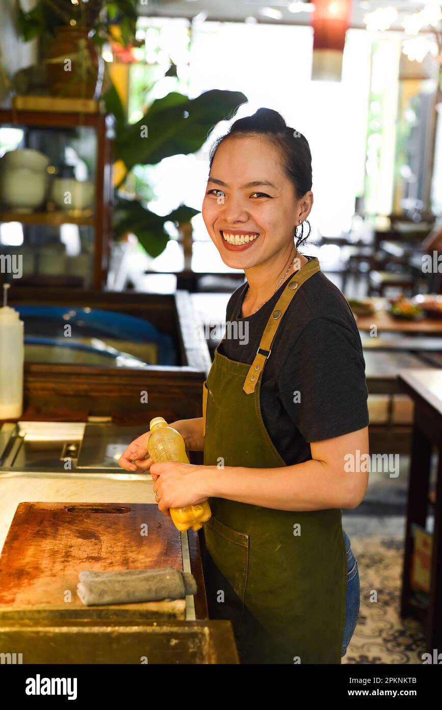 Cameriera felice vietnamita che lavora in una cucina di un caffè Foto Stock