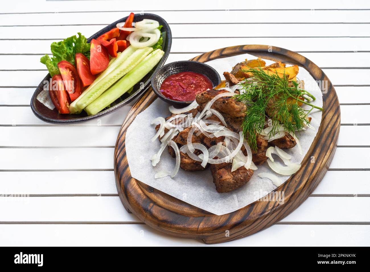 Shashlik di maiale con verdure alla griglia servito con insalata e ketchup su tavola di legno Foto Stock