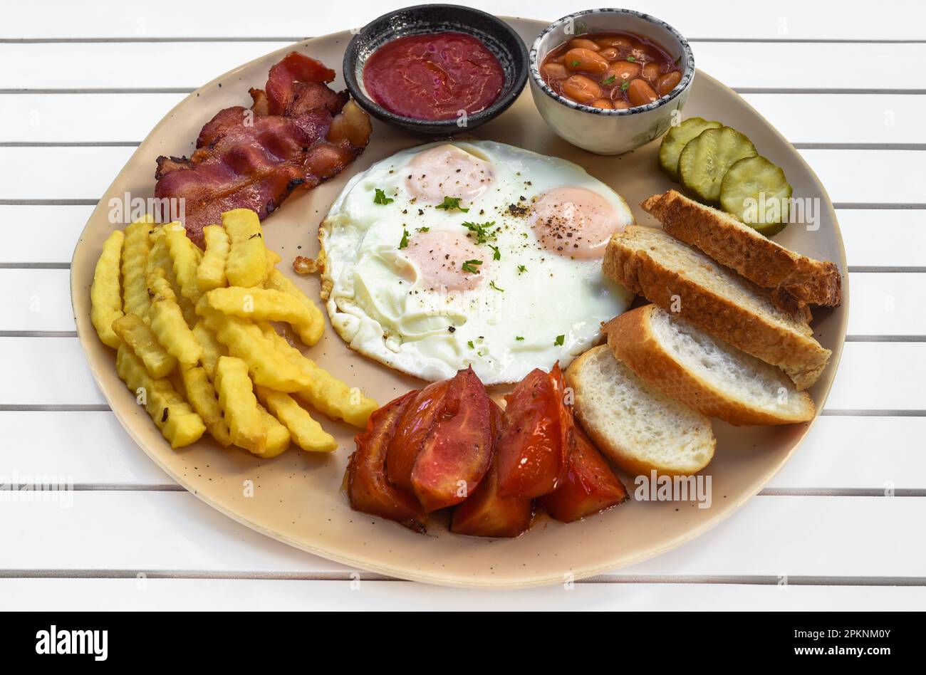 Colazione inglese sana con uova fritte, pancetta, patatine fritte, fagioli e pomodori primo piano Foto Stock