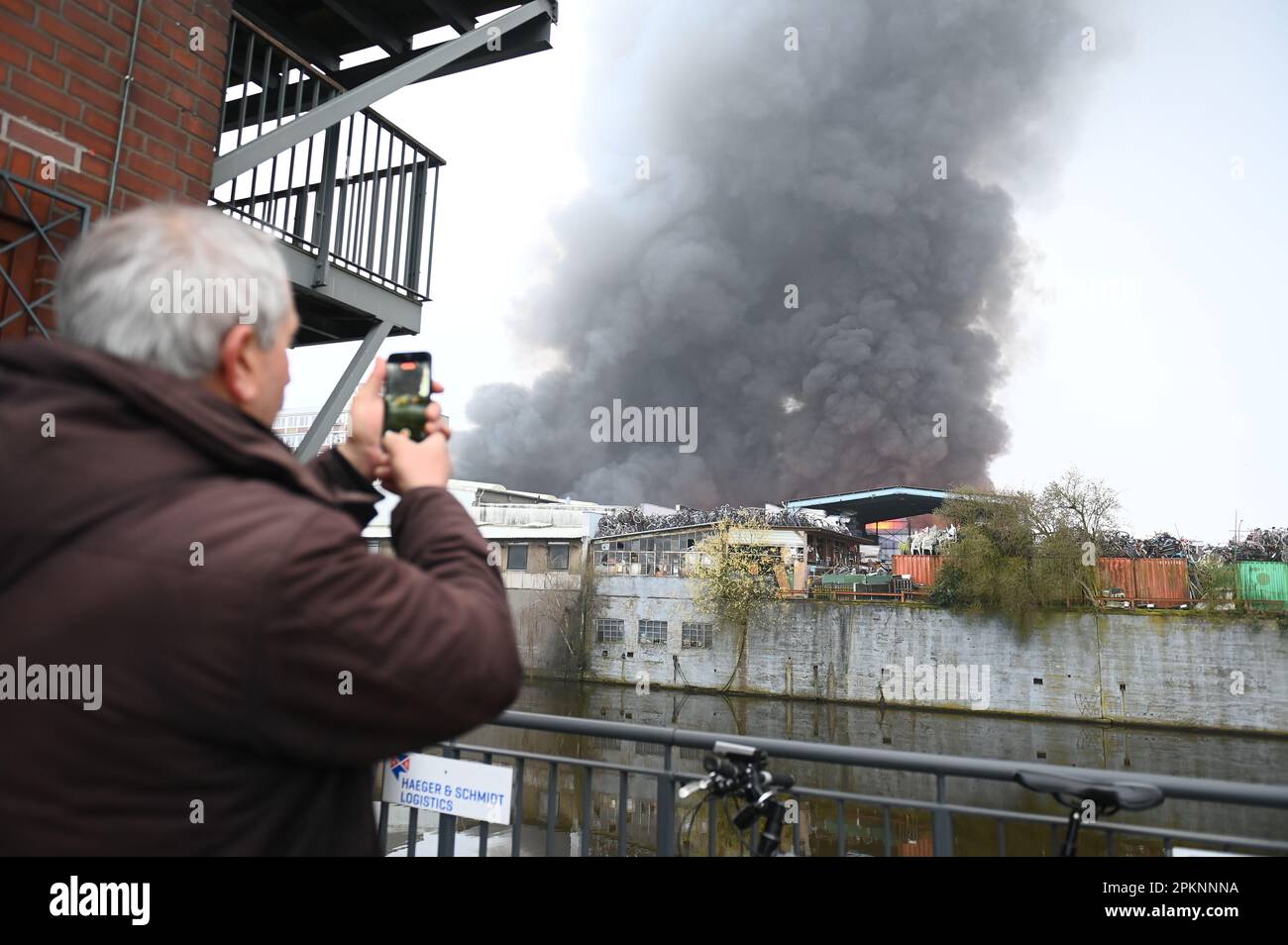 Amburgo, Germania. 09th Apr, 2023. Un uomo scatta una foto di un grande incendio ad Amburgo-Rothenburgsort con il suo cellulare. Diversi edifici sono stati in fiamme ad Amburgo-Rothenburgsort dalle prime ore del mattino. Credit: Jonas Walzberg/dpa/Alamy Live News Foto Stock