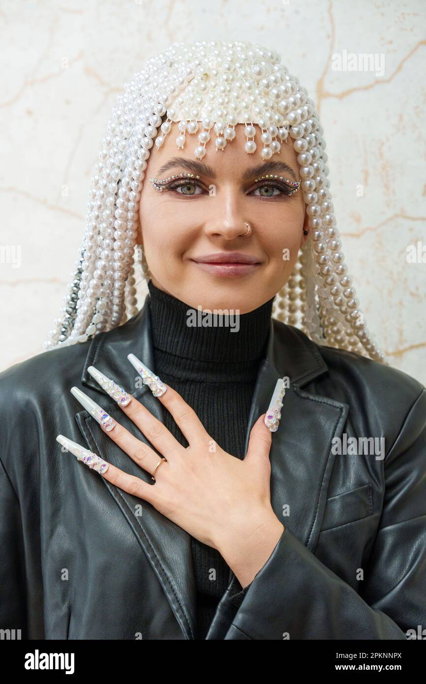 Ritratto verticale di un'artista femminile che mostra una mano con finte unghie decorate Foto Stock