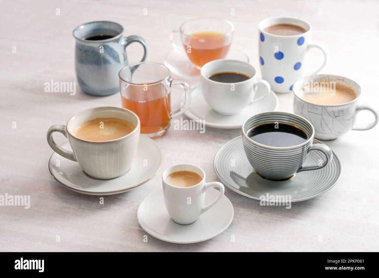 Gruppo di tazze e tazze diverse con caffè e tè bevande su un tavolo leggero, messa a fuoco selezionata, profondità di campo ristretta Foto Stock