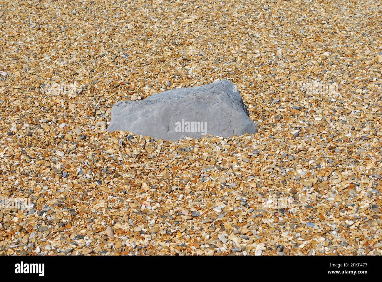 Roccia isolata sulla spiaggia in ghiaia Foto Stock