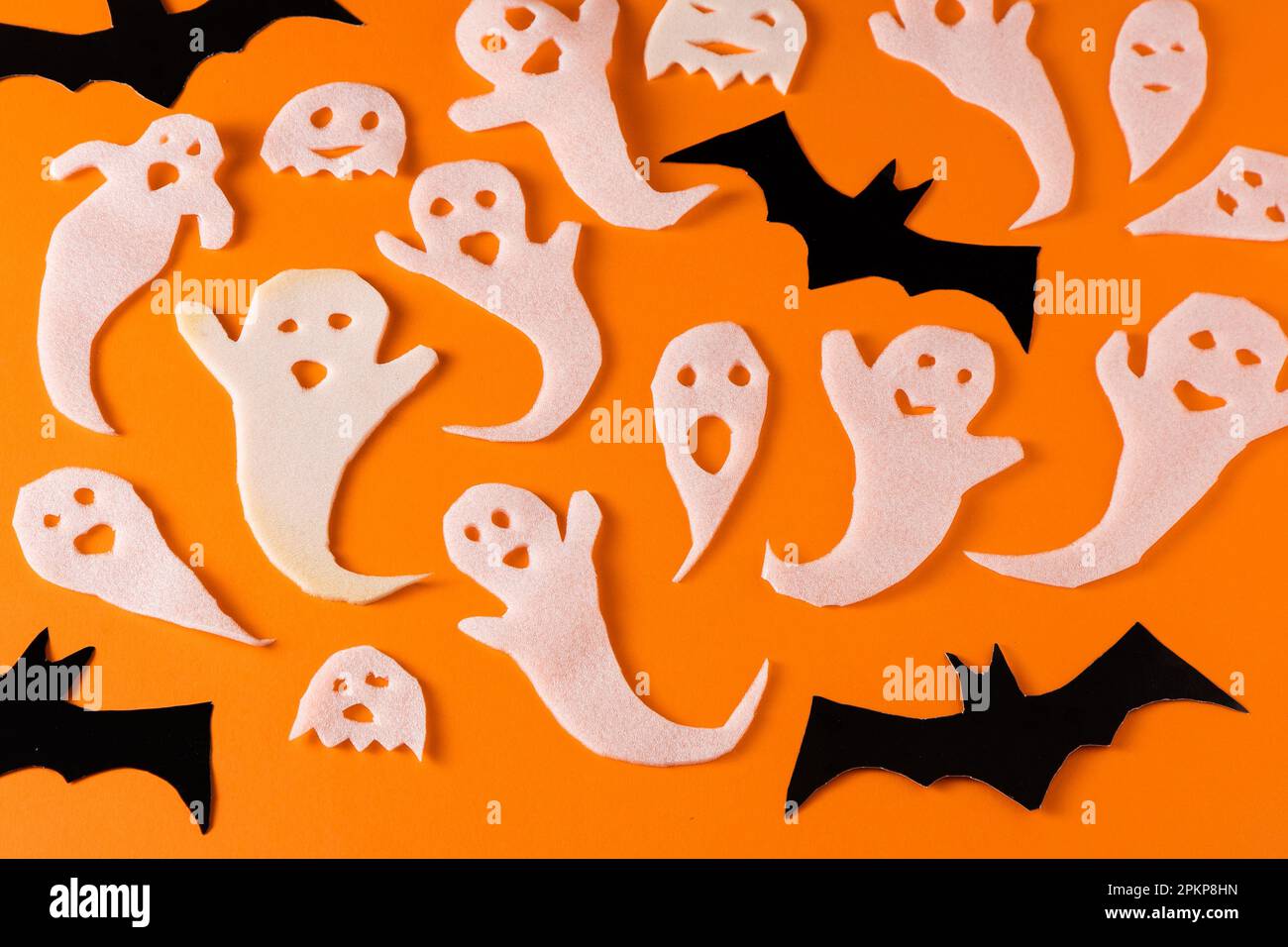 Fantasmi bianchi e mazza per la festa di Halloween. Immagine fantasma della carta di avvolgimento su sfondo arancione vista dall'alto. Fumetto Creepy Whisper. Fai-da-te fatto a mano. Impostare i caratteri boo. Foto Stock