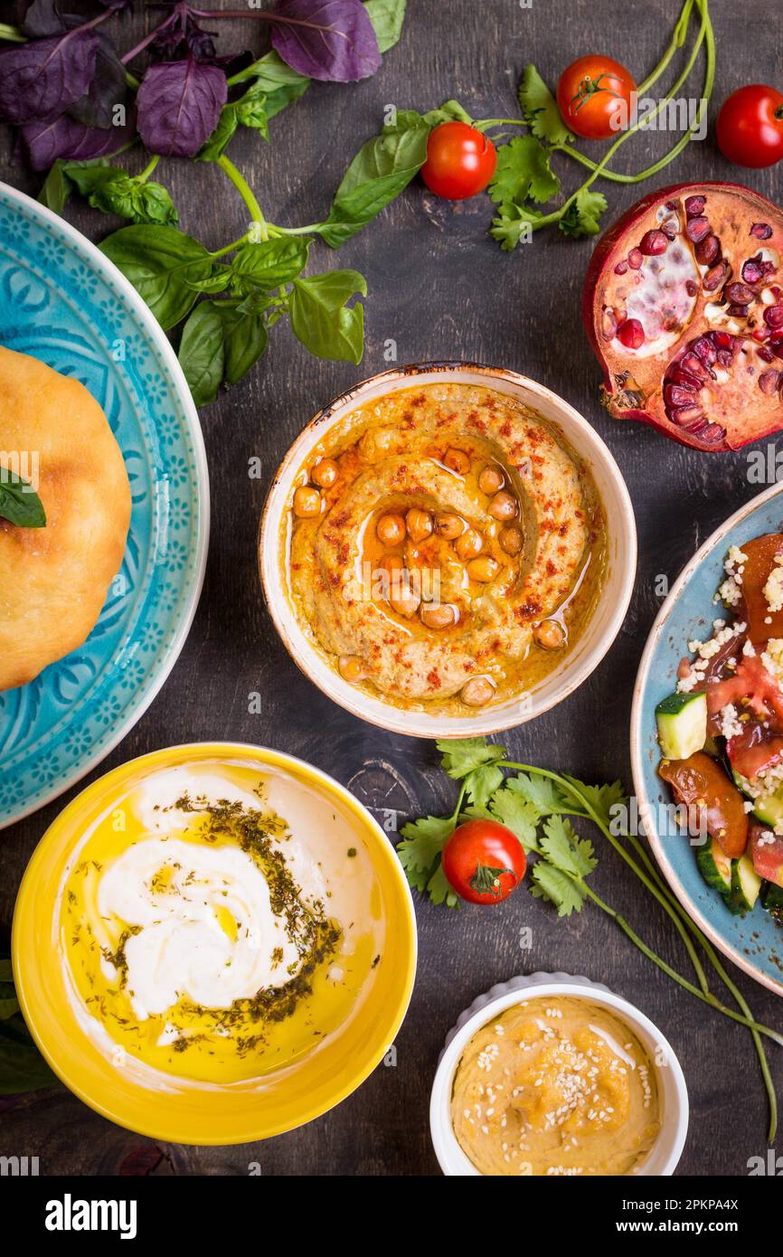 Tabella servita con medio orientali tradizionali piatti vegetariani. Hummus, la tahina, pitta, cuscus insalata e latticello dip con olio di oliva. Cena di gala Foto Stock