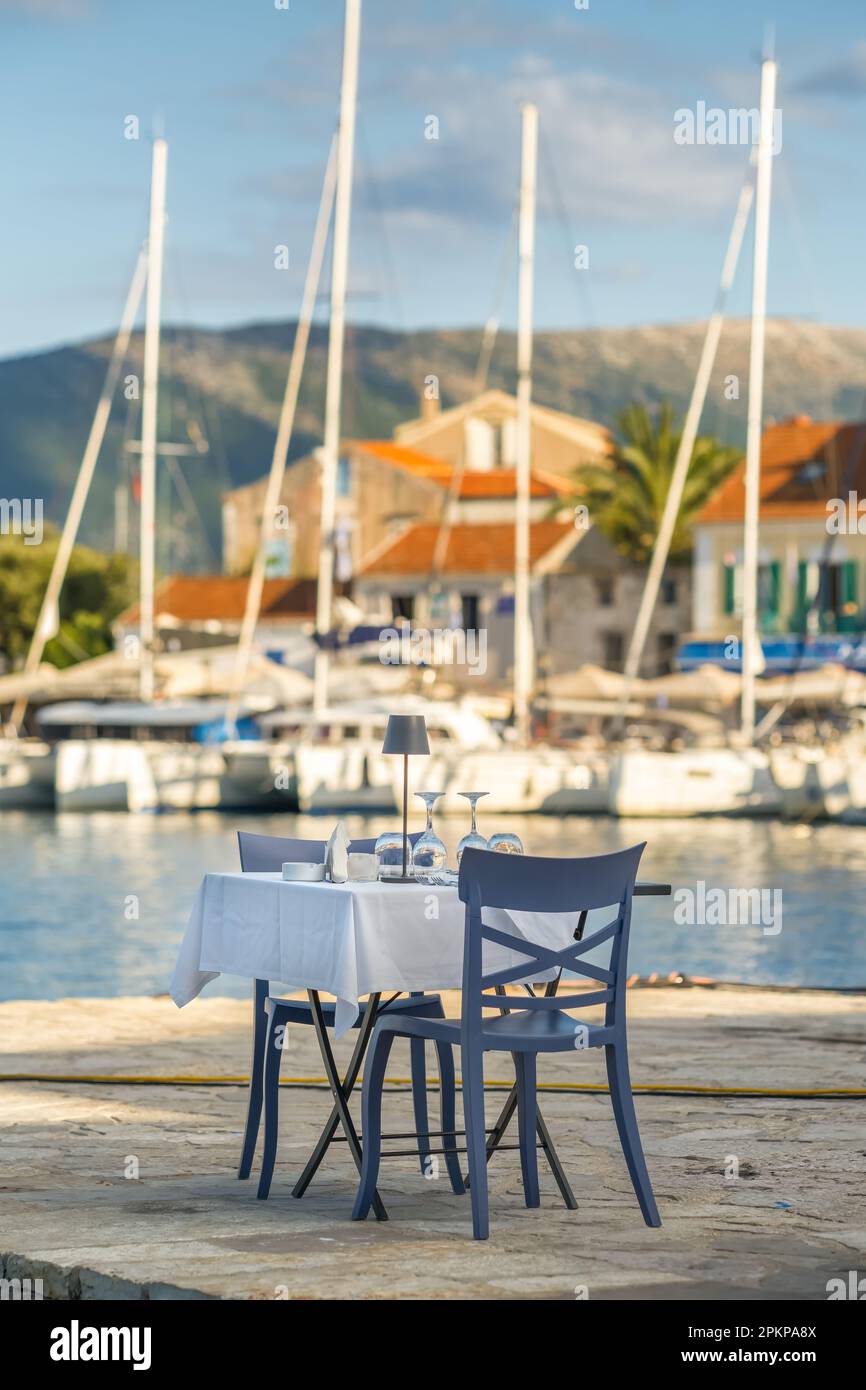 Tavolo in una caffetteria con tovaglia, bicchieri vuoti e piatti sulla riva del mare Foto Stock