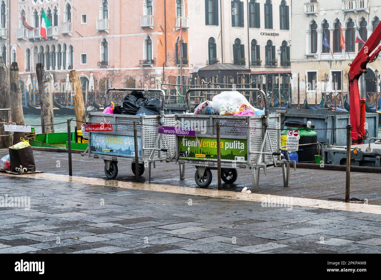 Venezia, Italia - 23 febbraio 2023: Bidoni dei rifiuti riempiti di rifiuti vicino al Canal Grande a Venezia pronti per essere raccolti. Foto Stock