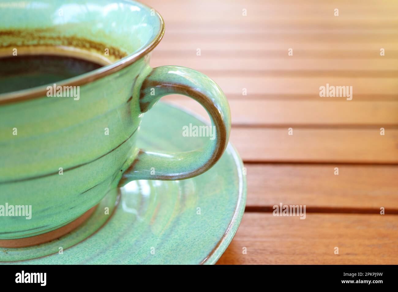 Primo piano di caffè caldo in una tazza di ceramica verde isolata su un tavolo di legno Foto Stock