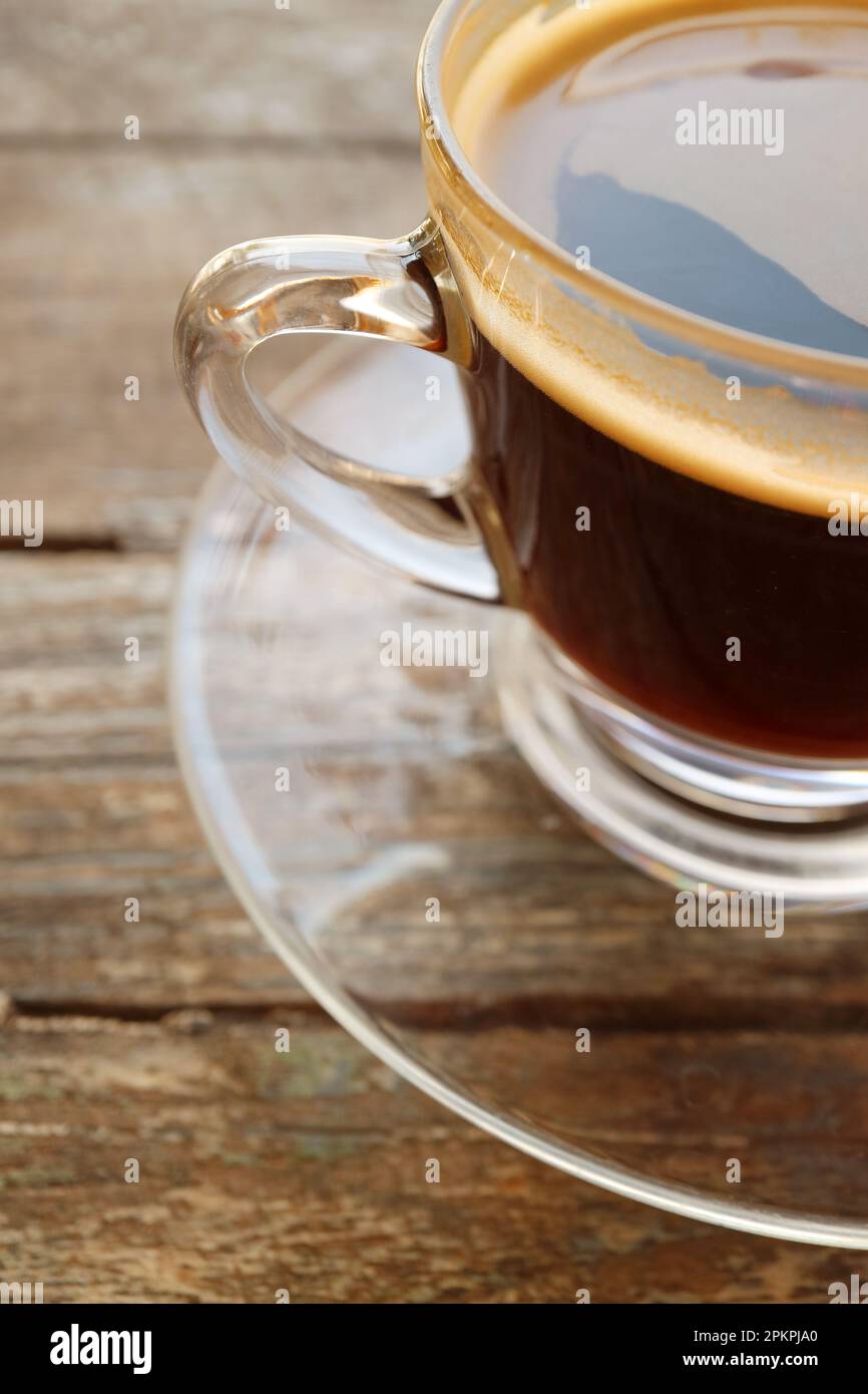 Caffè nero caldo in una tazza trasparente isolata su un tavolo di legno Foto Stock