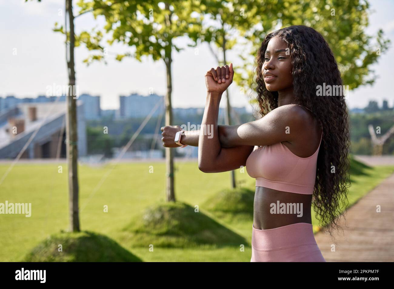 Giovane donna africana modello in forma facendo riscaldamento esercizio in piedi nel parco cittadino. Foto Stock