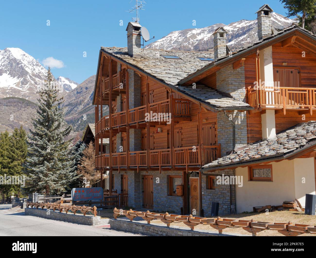 Grande proprietà in legno e pietra con balcone e tetto in ardesia con più camini a Cogne, Parco Nazionale del Gran Paradiso in Valle d'Aosta, Italia Foto Stock