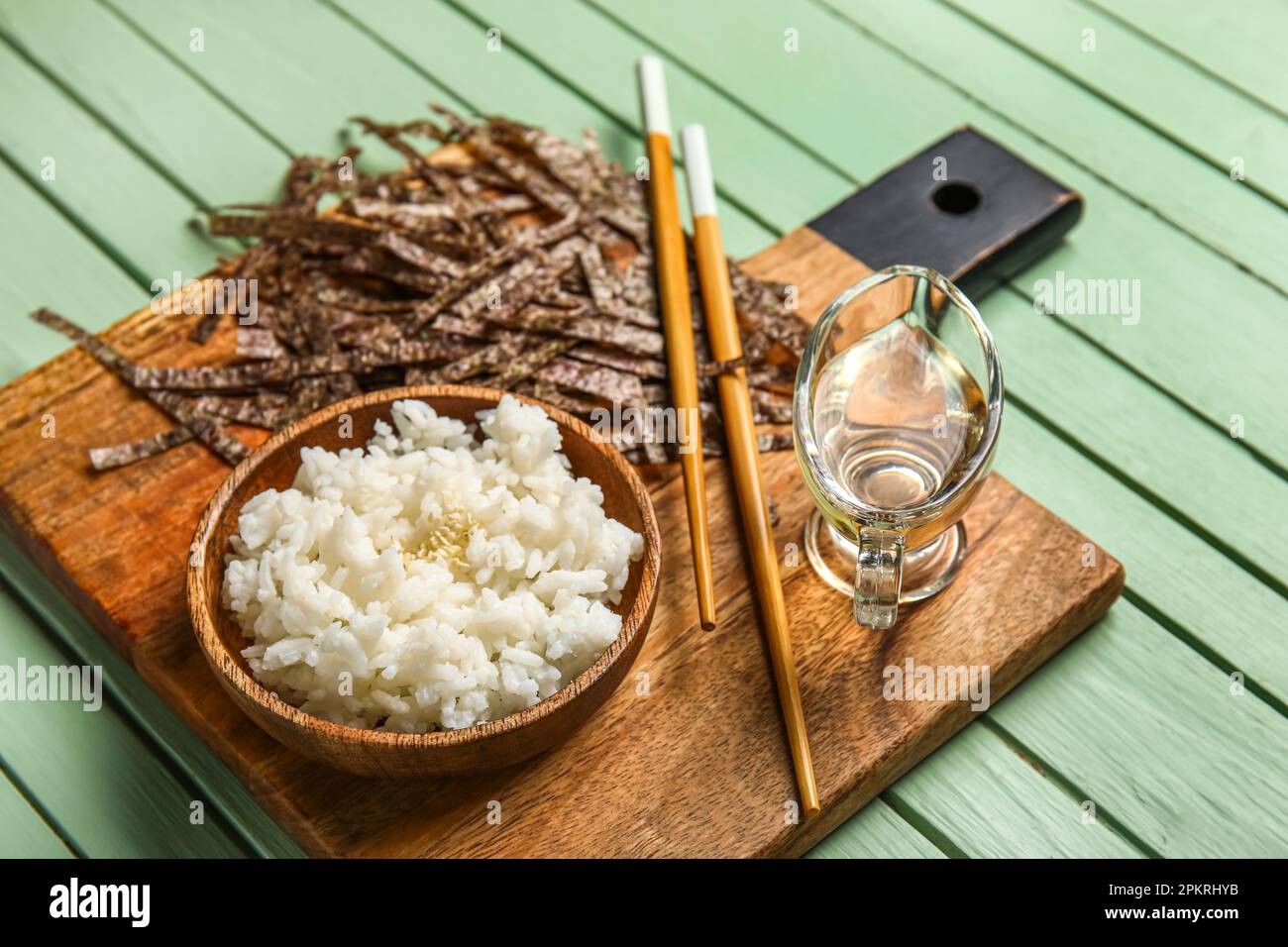 Tagliere con barca con sugo di aceto di riso, bacchette e fogli di nori  tagliati su sfondo di legno colorato, primo piano Foto stock - Alamy