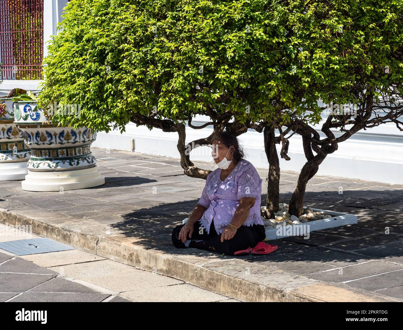 Il clima caldo e umido a Bangkok, in Thailandia, può essere difficile anche per la gente del posto. Una donna tailandese sta riposando all'ombra sotto un albero al Wat Aru Foto Stock