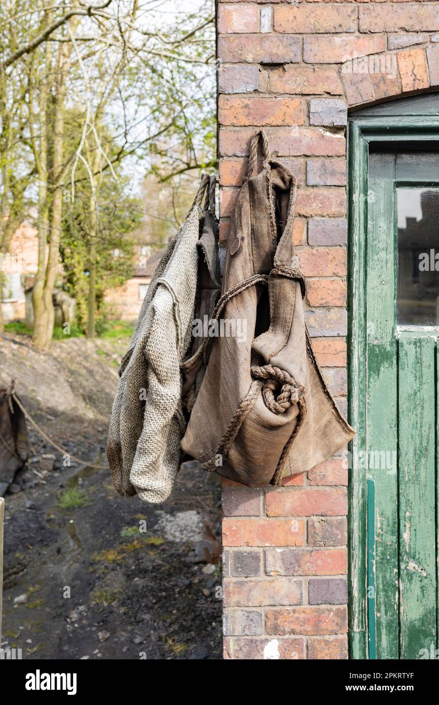 sacchi di carbone vuoti appesi su un muro di mattoni Foto Stock