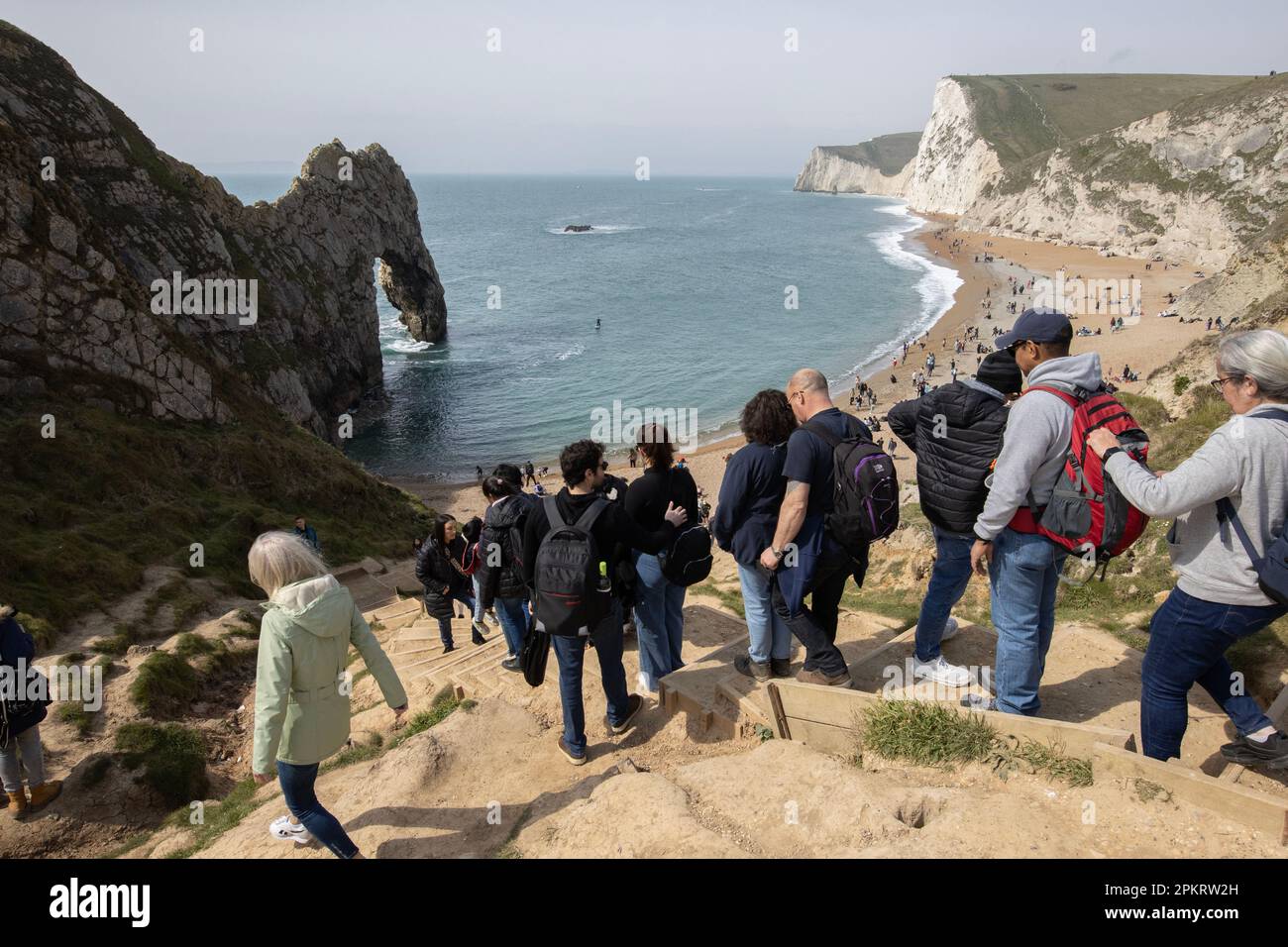 Folle di turisti scendono su Durdle Door, sulla Jurassic Coast durante il fine settimana di festa della Easter Bank, 2023, Inghilterra, Regno Unito Foto Stock