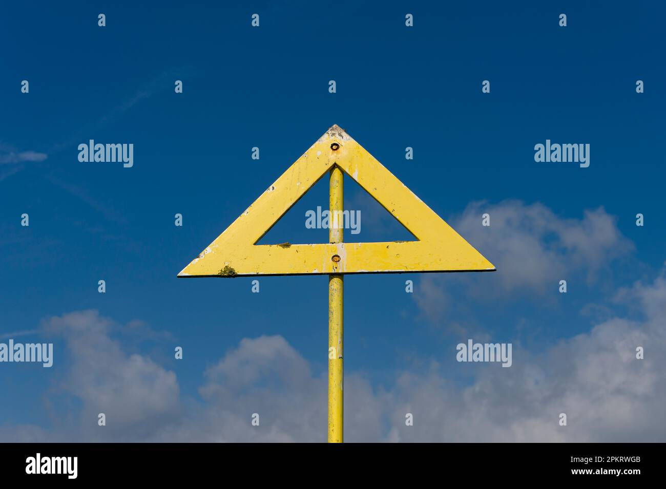 Freccia gialla triangolare contro un cielo blu Foto Stock