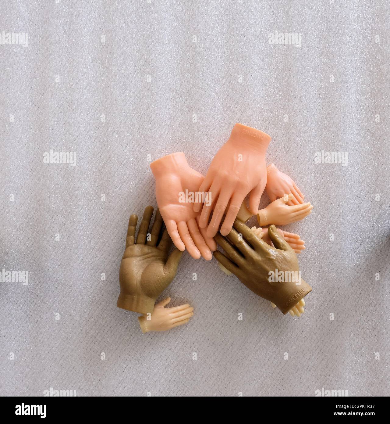 Mani giocattolo in plastica in diverse tonalità della pelle; aiuto, assistenza, armonia, concetto di diversità; le mani di un dito molto piccole. Foto Stock