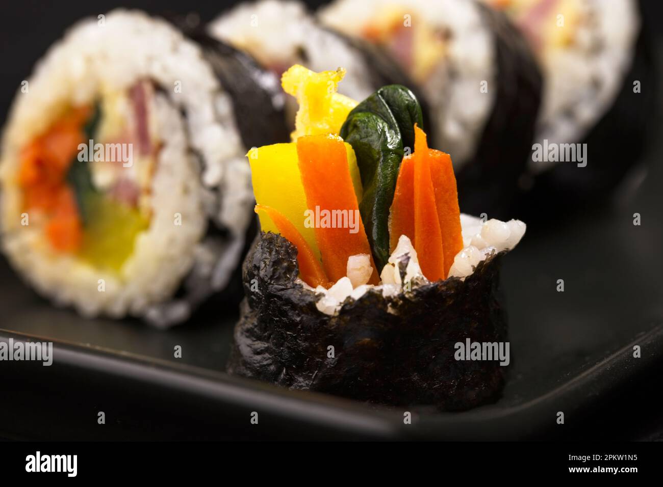 Un primo piano del pezzo finale di un trattamento coreano chiamato Kimbap. Cibo fatto con riso al vapore, impacco di alghe, carota, spinaci, uova, e sottaceto di radi cinesi Foto Stock
