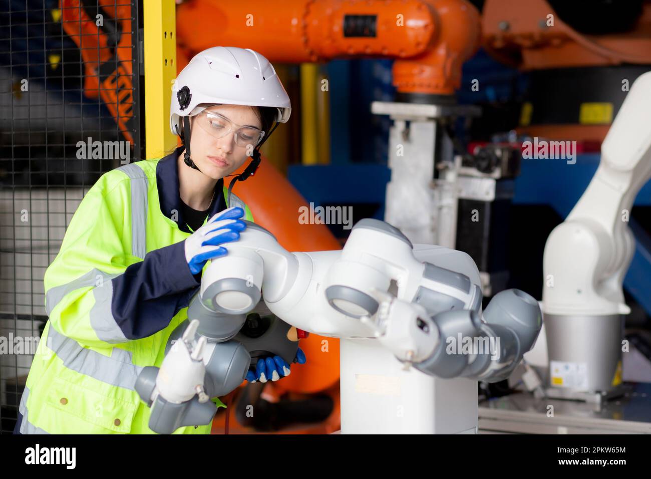 Giovane ingegnere donna controllo e manutenzione macchina robot armi intelligenza tecnologia e innovazione in fabbrica industriale, persone o tecnico ex Foto Stock