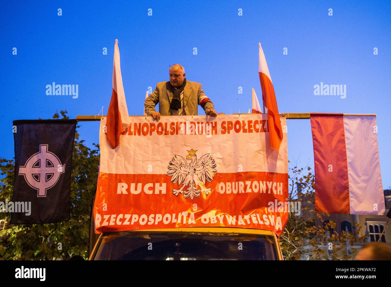 Un dimostratore si trova su una piattaforma automobilistica con bandiere polacche e celtiche (supreminazione bianca) attaccate durante la protesta. Il 11 novembre, Giornata dell'Indipendenza Polacca, è stata organizzata la Grande marcia dell'Indipendenza. I manifestanti chiedono un ritorno ai valori e all'identità tradizionali polacchi, invocando spesso il cattolicesimo e il nazionalismo come parti importanti della loro visione del mondo. Molti di loro sottoscrivono ideologie politiche di estrema destra e sono affiliati con organizzazioni come la rinascita nazionale della Polonia e gli hooligan polacchi della gioventù e del calcio. Tuttavia, va notato che non tutte le partecipazioni Foto Stock