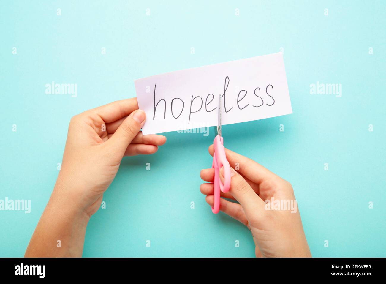 Le mani della donna tengono una carta con la parola senza speranza, tagliala con le forbici per fare speranza. Vista dall'alto Foto Stock