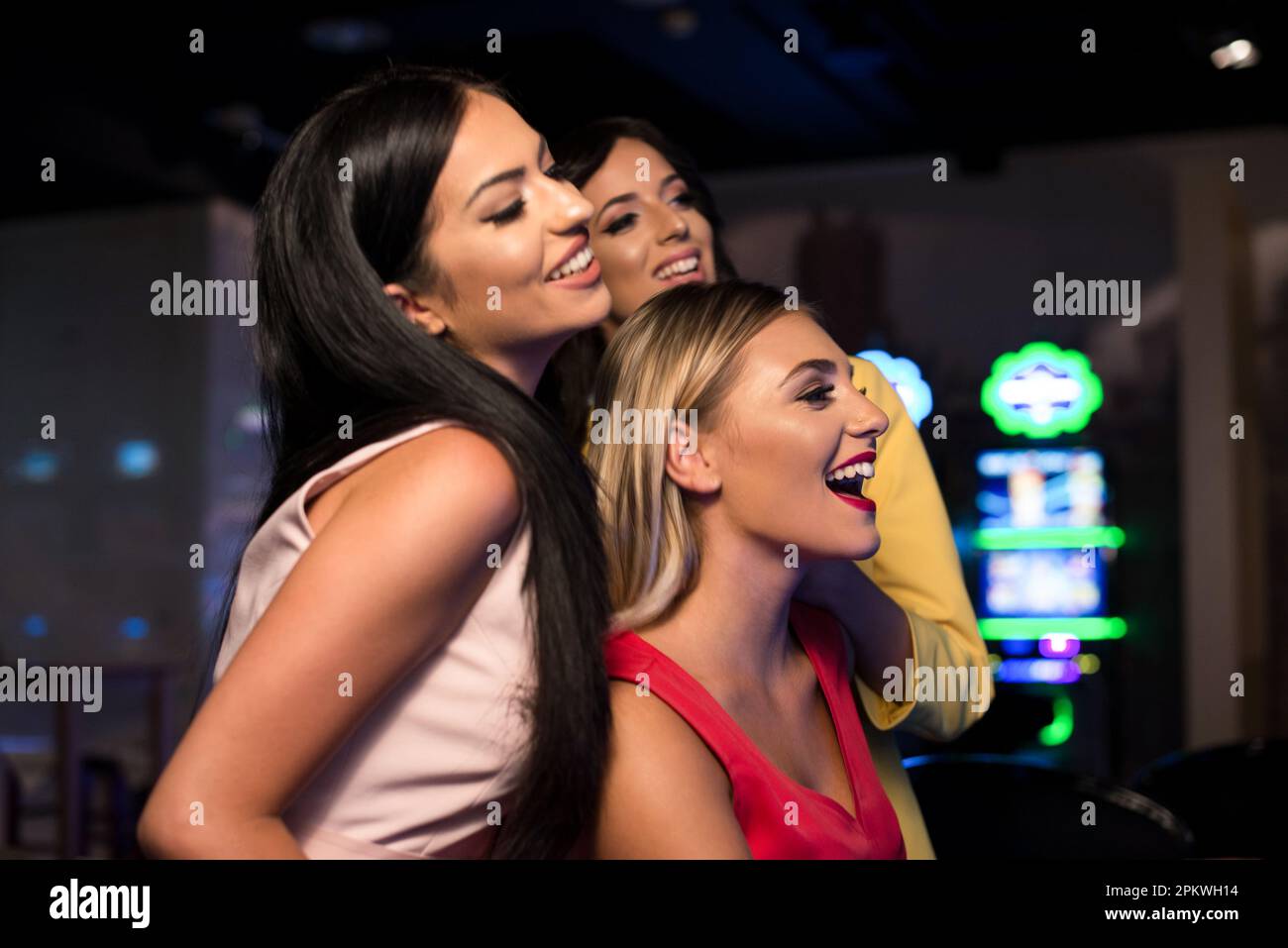 Giovani Donne di notte alla macchina automatica in un casinò e celebrare Foto Stock