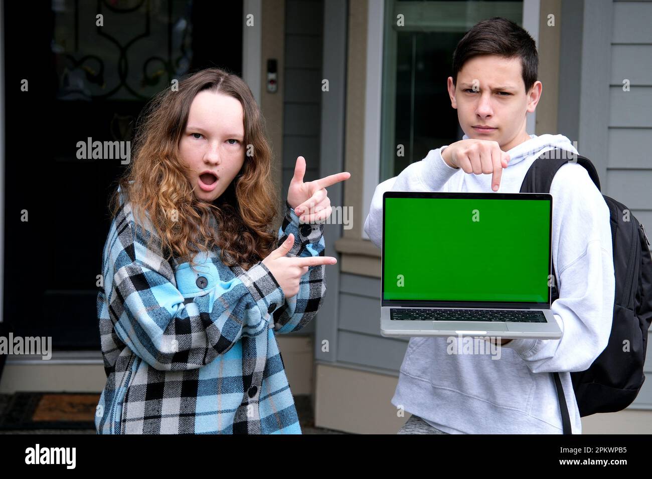 ragazzo adolescente ragazza adolescente ballare gioire mostrando dita verde schermo chroma chiave sul computer sulle spalle zaino scuola di apprendimento sincero risate pubblicità online podcast di apprendimento sulla piattaforma Foto Stock