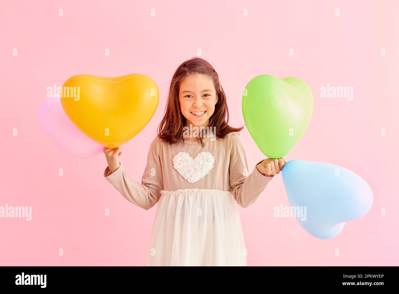 Giovane ragazza sorridente che tiene palloncini di cuore Foto Stock