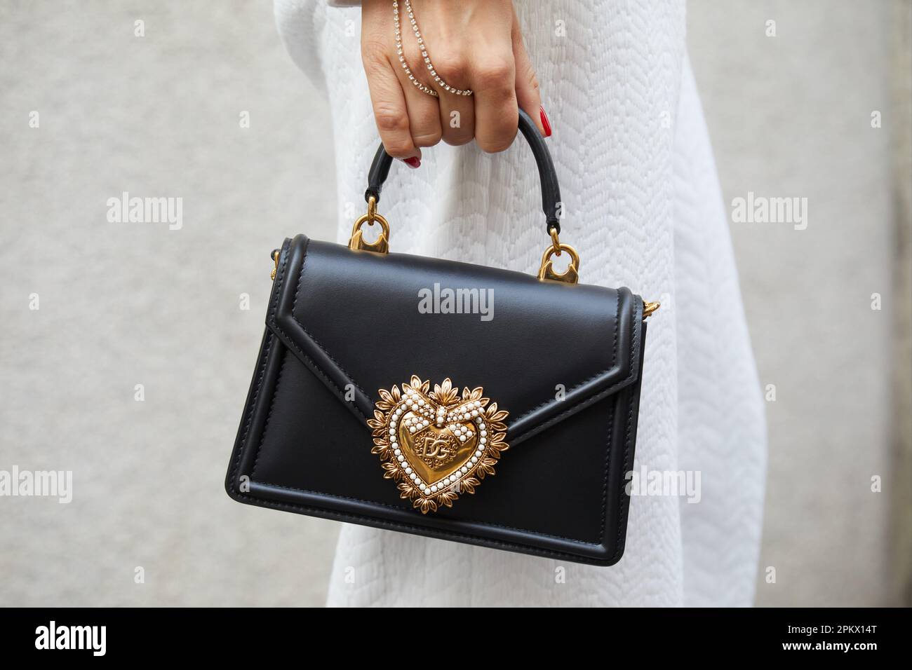 MILANO, ITALIA - 23 FEBBRAIO 2023: Donna con borsa Dolce e Gabbana con cuore dorato prima della sfilata Genny, Milano Fashion Week Street Style Foto Stock