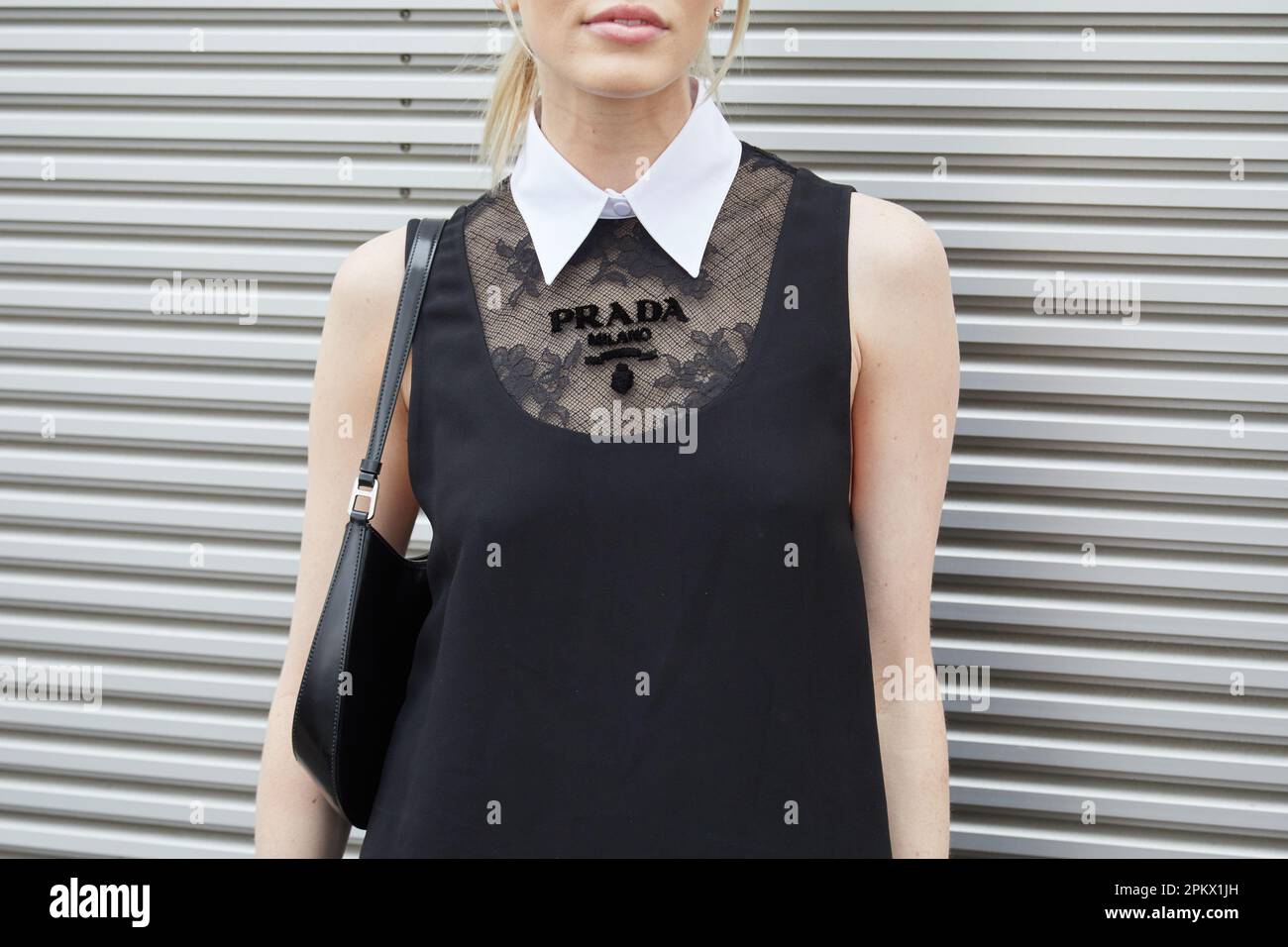 MILANO, ITALIA - 23 FEBBRAIO 2023: Donna con abito Prada con colletto bianco prima della sfilata Prada, Milano Fashion Week Street Style Foto Stock