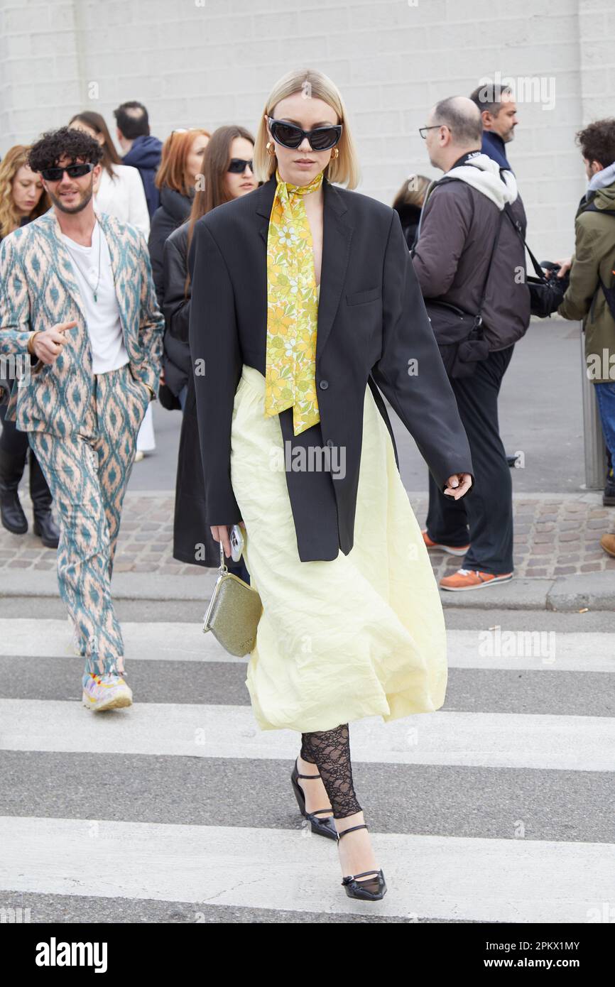 MILANO, ITALIA - 23 FEBBRAIO 2023: Donna con gonna gialla e giacca nera prima della sfilata Prada, Milano Fashion Week Street Style Foto Stock