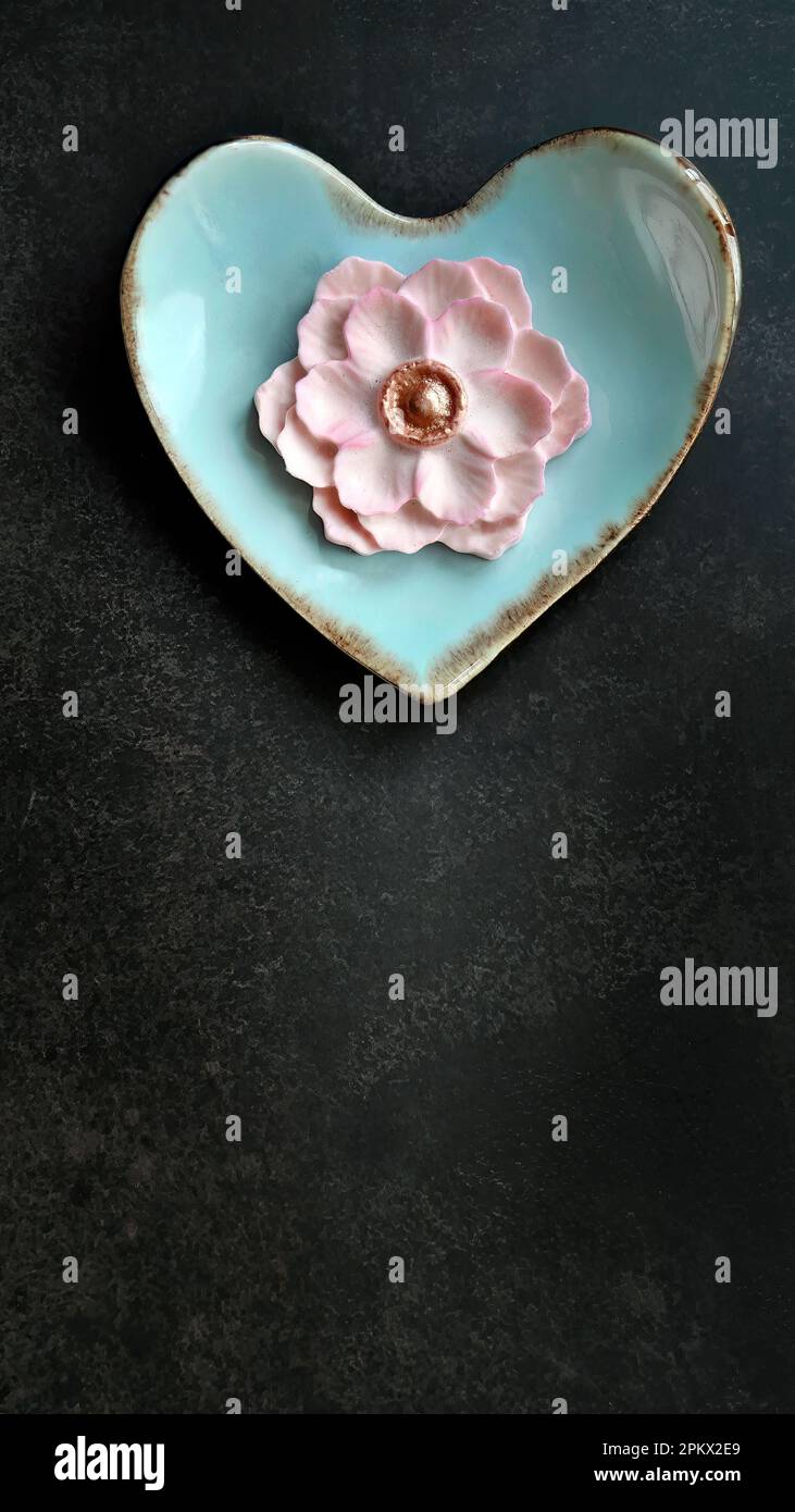 Sapore di latte di cocco, colore rosa pastello, Sam Pan Nee tradizionale spuntino artigianale tailandese su piatto blu pastello a forma di cuore, sfondo scuro, immagine verticale Foto Stock