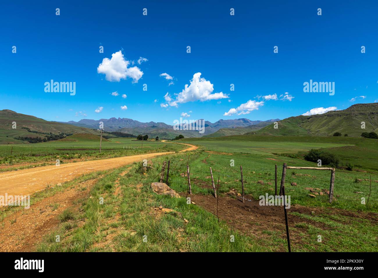 Strada di ghiaia vento attraverso il paesaggio verde alla montagna Drakensberg Sud Africa Foto Stock