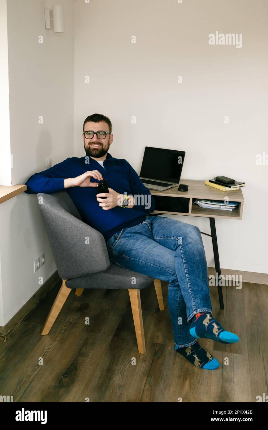 l'uomo si siede alla scrivania con un computer portatile e libri e pensa al lavoro Foto Stock