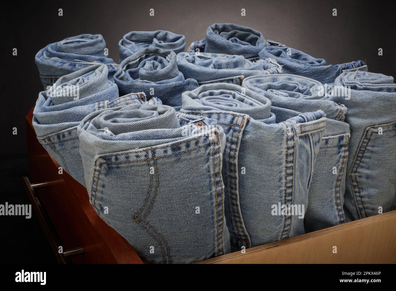 Jeans blu sbiaditi, arrotolati e organizzati Foto Stock