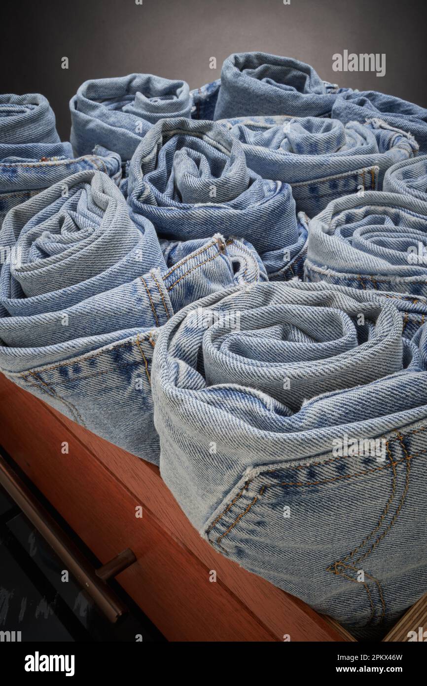 Jeans blu sbiaditi, arrotolati e organizzati Foto Stock