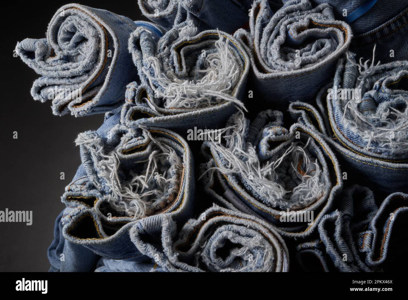 Jeans blu sbiaditi, arrotolati e organizzati Foto Stock