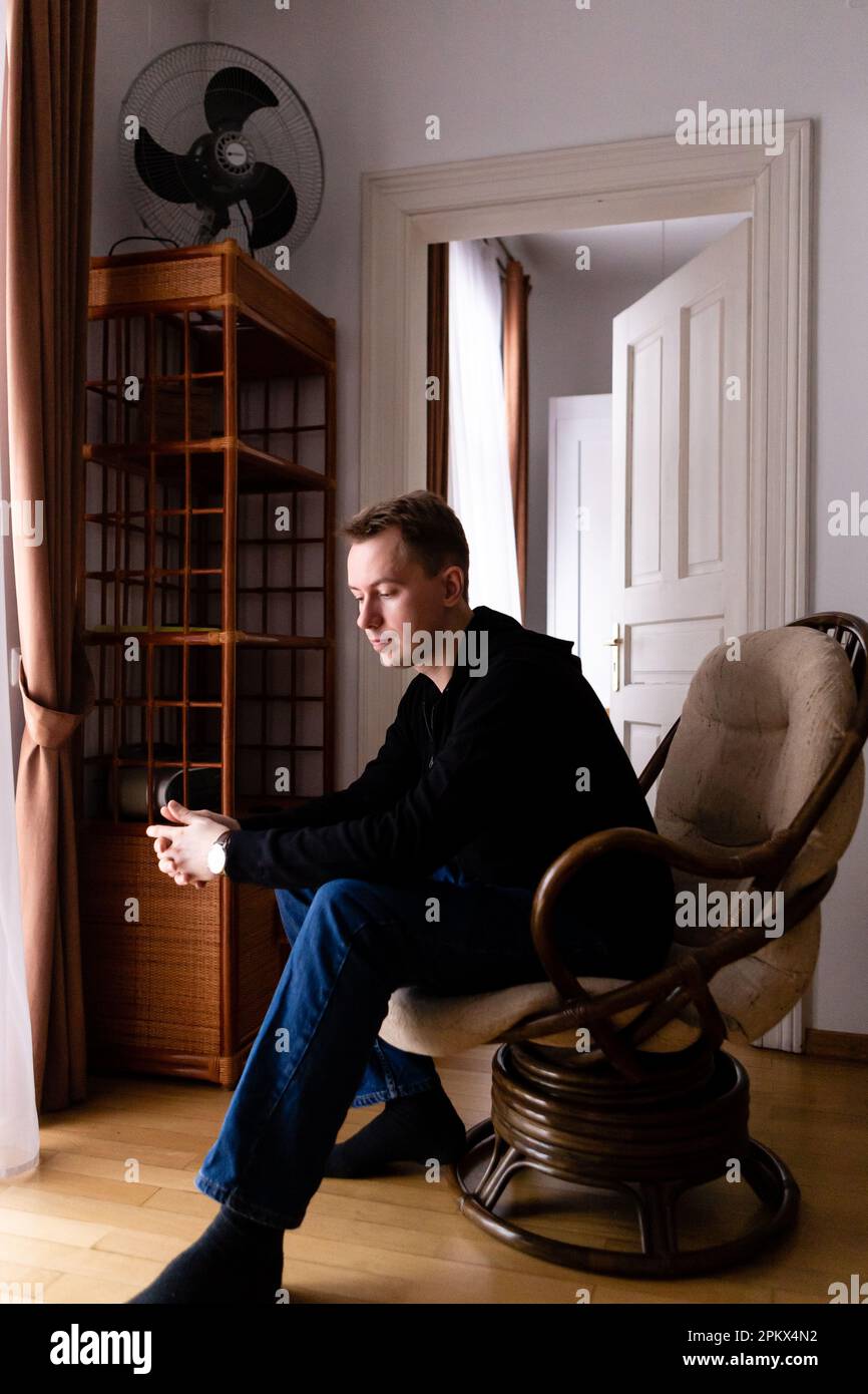 uomo in un maglione nero e jeans blu da solo nel suo appartamento Foto Stock