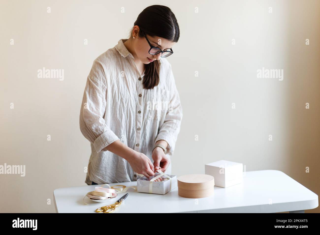 l'imprenditore di pasticcerie femminile confezionerà i suoi dolci in scatole di confezionamento Foto Stock